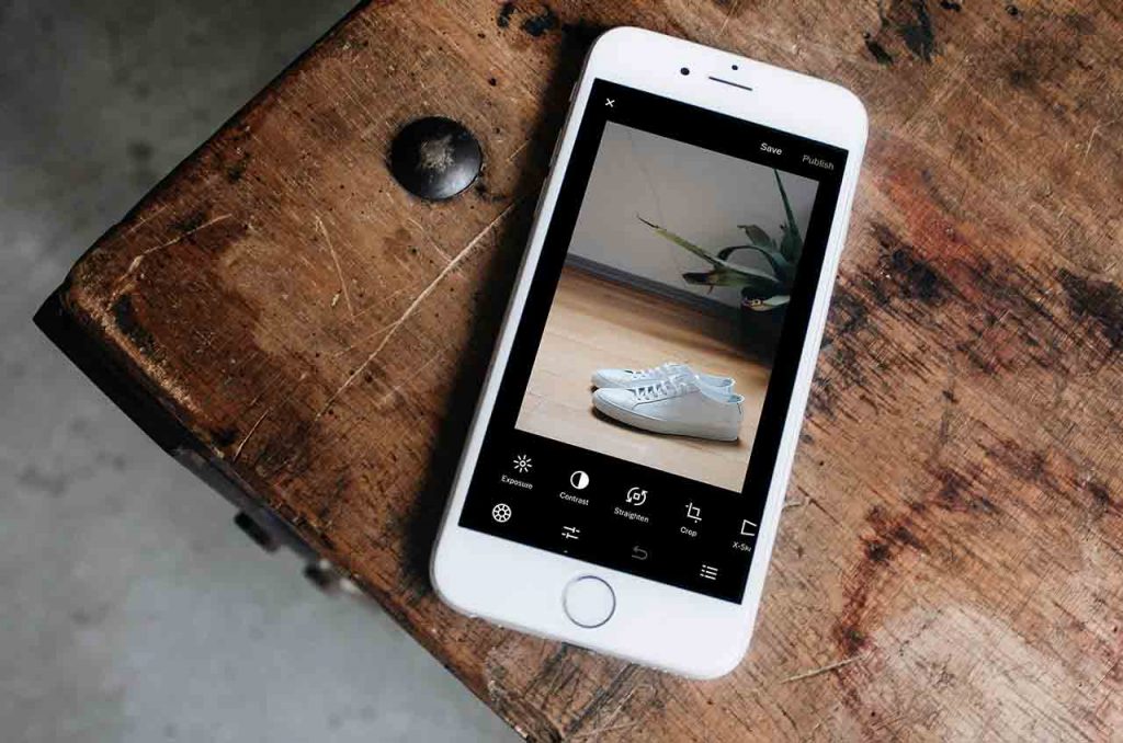 iPhone liegt auf dem Tisch und geöffnet ist eine App zum Fotos bearbeiten